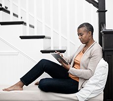 woman sitting on stairs looking at Schafts on a tablet